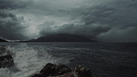 Stormy waves and dramatic storm clouds over a distant, dark, lonely island. Cinematic, filmic, fantasy scene. Montenegro, September.