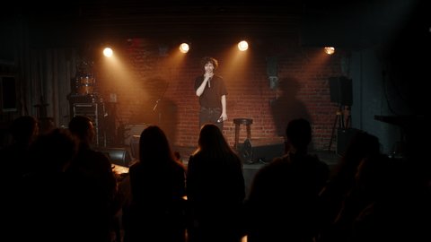DOLLY Young Caucasian male comedian entering stage and greeting audience, performing his stand-up monologue inside a small venue. Shot with ARRI Alexa Mini LF with 2x anamorphic lens