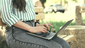 Close up video of young woman sitting outdoors and using laptop.