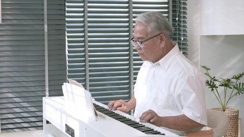 Senior Asian Man Playing Piano During Relaxation Time.