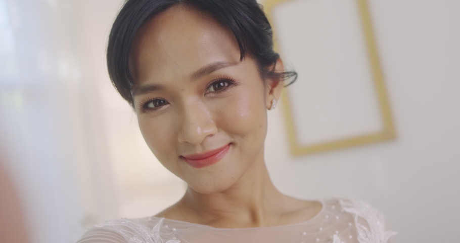 Happy Beautiful Asian Bride Talking To Her Friend By Smartphone Video Call On Wedding Day Ceremony.