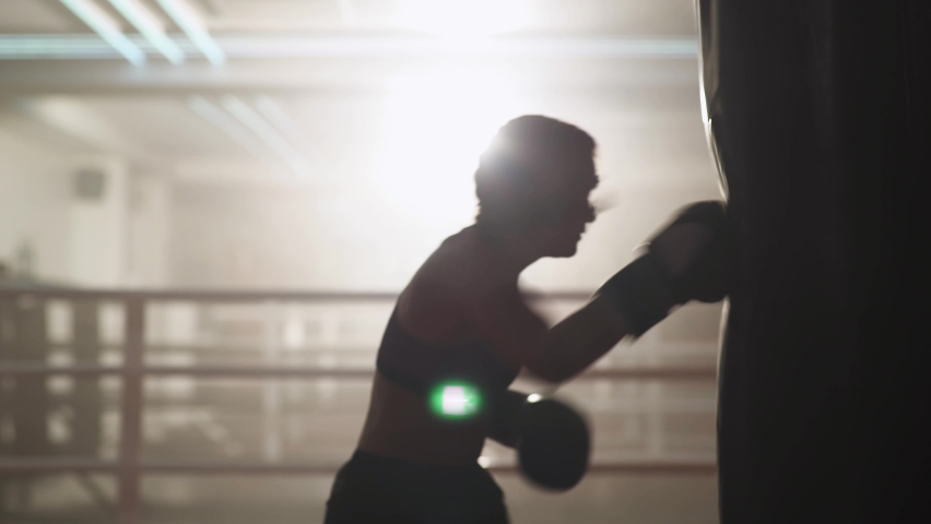 Blurred view, woman fighter trains his punches, beats a punching bag, training day in the boxing gym, strength fit body, the female strikes fast. | Shutterstock HD Video #1073939237