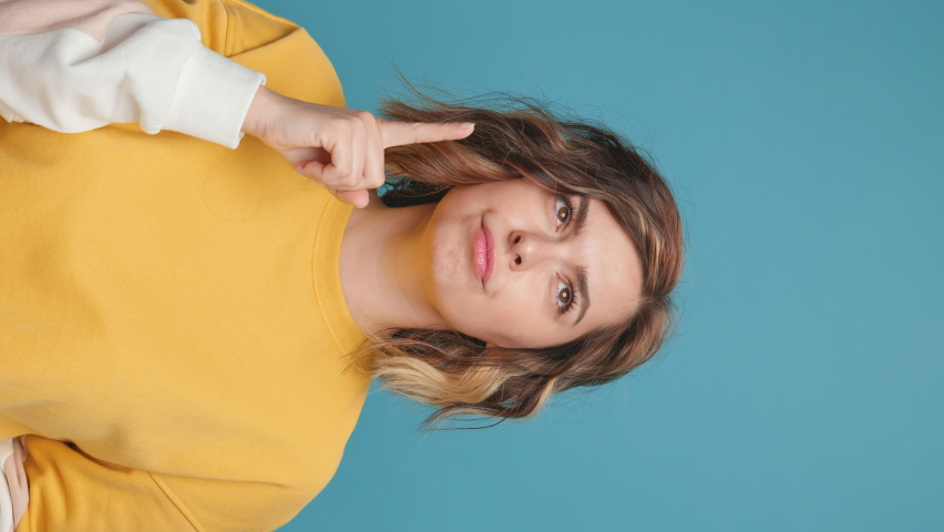Look Young woman blogger index finger up gesture copy space advertising products  surprise Doubting Emotion, smile looks at camera delight admiration on blue background. Share video to social media Royalty-Free Stock Footage #1073941961