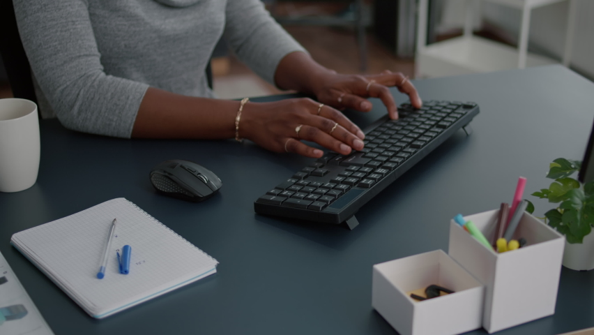 Closeup of african american student hands working at communication project typing information on keyboard using computer sitting at desk in living room. Woman searching business email Royalty-Free Stock Footage #1073944832