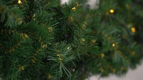 Close-up view 4k stock video footage of green branches of holiday Christmas tree decorated with elegant orange electric blinking led lights garland ornament. Abstract Xmas background - Powered by Shutterstock - Get 15% off with code: PIKWIZARD15