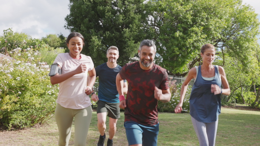 Healthy group of multiethnic middle aged men and women jogging at park. Happy mixed race couples running together. Mature friends running together outdoor. Royalty-Free Stock Footage #1073952977