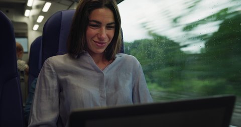 Cinematic shot of business woman sending emails for job on laptop while travelling by train for work. Concept of transportation, travel, business and finance, technology, connection, network, tourism.