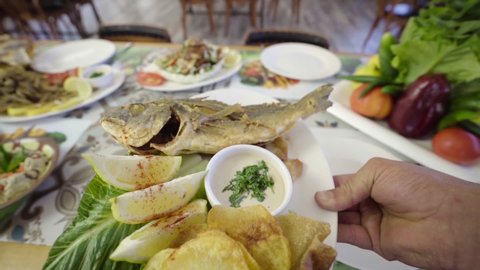 Serving a dish of roasted sea bream fish with potatoes and sauce on a restaurant table. Middle Eastern food, Lebanese cuisine