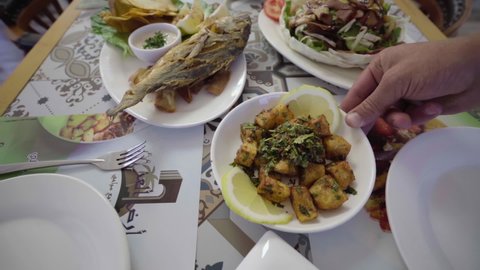 Serving a dish of roasted sea bream fish with various Lebanese cuisine appetizer dishes on a restaurant table. Middle Eastern food