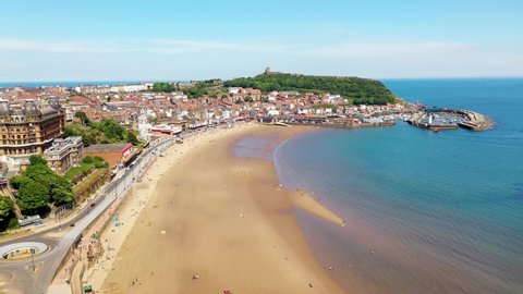 Aerial drone footage of the beach front in the town of Scarborough in North Yorkshire, England UK showing people relaxing and having fun on the beach on a sunny summers day