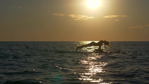 sup boarding, doing yoga on a sup board at sea at sunset, young woman on a surf board, leisure activity, water sports, vacations, summer holiday concept