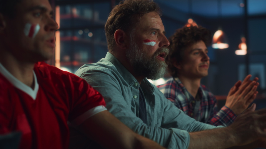 At Home Three Joyful Sports Fans with Painted Faces Sitting on a Couch Watch Game on TV, Celebrate Victory when Sports Team Wins Championship. Friends Cheer, Shout. Close-up Mid Portrait Shot