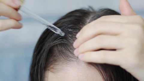 woman applies oil to hair roots, the process of applying oil to the scalp, woman applies oil to hair roots