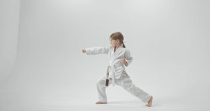 The girl stands in the lunge and strikes with her hands straight. The girl is turned to the side. Video of a girl in full growth.