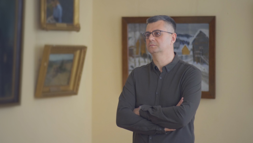 Man in art gallery, consider hanging pictures on the walls.