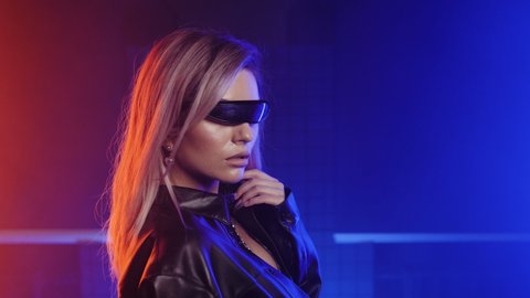 Future nightlife visor glasses eyewear nightclub stylish blonde girl. Neon red and blue cyberpunk woman on futuristic background. Night club person in cyber punk eye wear visors. 2077 modern goggles.
