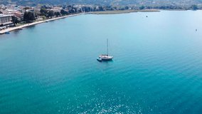 A boat on blue lake of Ohrid, North Macedonia. Sun light is glittering on water surface. Peaceful moment of travel or trip. Beautiful scenic took with aerial drone 4K 30fps.