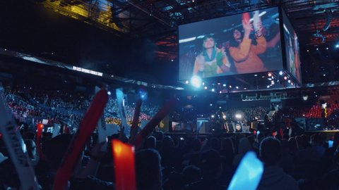 Hamburg, Germany; April 23rd, 2017: League of Legends esports. European Finals beginning. Crowded stadium to witness the game. Amazing atmosphere, people applauding with thundersticks. Tracking shot.
