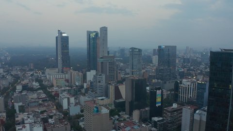 Forwards flying drone towards group of skyscrapers in downtown. Aerial view of tall office buildings and morning cityscape in background. Mexico city, Mexico in 2021