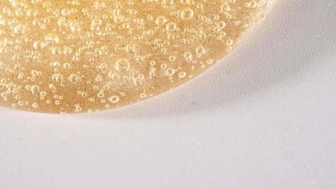 Yellow Transparent Cosmetic Gel Cream With Molecule Bubbles Flowing On The Plain White Surface. Macro Shot