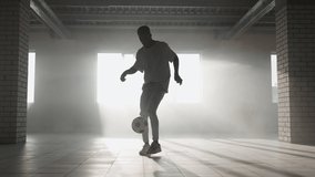 Black man football soccer player practicing tricks, kicks and moves with ball inside empty covered parking garage. African boy freestyle training in Urban city . Slow motion RAW graded footage