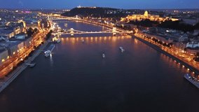 Cinematic 4K aerial drone night dolly footage of river cruise ships, Castle Hill, Buda Castle, Gellért Hill and the Citadella with the Danube river, bridges lit up after sunset in Budapest, Hungary