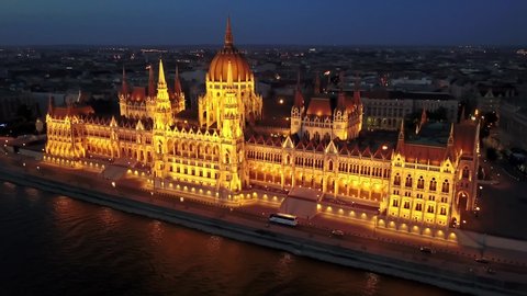 Cinematic 4K aerial drone night orbiting clip of the illuminated Hungarian Parliament Building with the Danube river, bridges lit up after sunset in Budapest, Hungary