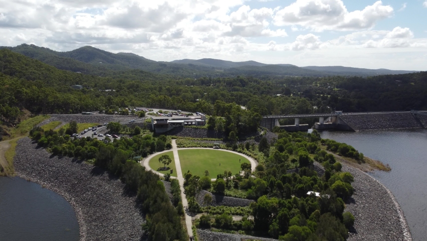Flying over a green field near a dam wall