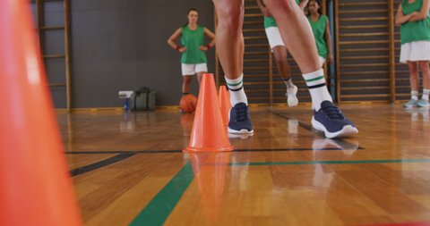 Mid section of diverse female basketball team practice dribbling ball. basketball, sports training at an indoor court.
