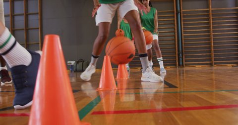 Mid section of diverse female basketball team and coach practice dribbling ball. basketball, sports training at an indoor court.