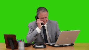 Elderly businessman working at his desk against a green screen