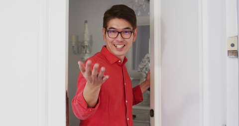 Happy asian man opening front door, smiling and greeting visitor to home. happy family, domestic life at home.
