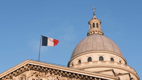 French flag waving in the air on the Pantheon with cupola in Paris blue sky sunny day