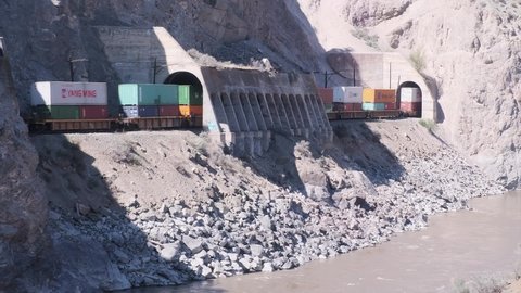 Spences Bridge , British Columbia , Canada - 04 22 2021: Container cars on freight train pass through rocky riverside tunnels