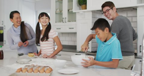 Happy asian parents in kitchen with son and daughter, baking together. happy family, at home in isolation during quarantine lockdown.