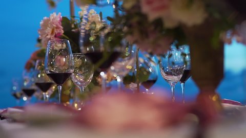Organize an evening party with flower red wine glass wedding reception. Close up Wedding decor beach set up candle catering chair dining dinner outside. copy space 2022.
