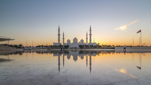 Sheikh Zayed Grand Mosque in Abu Dhabi day to night transition timelapse after sunset, UAE. Evening view from Wahat Al Karama with reflections on water