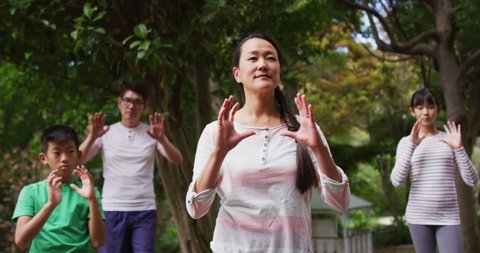 Happy asian parents exercising in garden with son and daughter, practicing tai chi together. happy family, at home in isolation during quarantine lockdown.