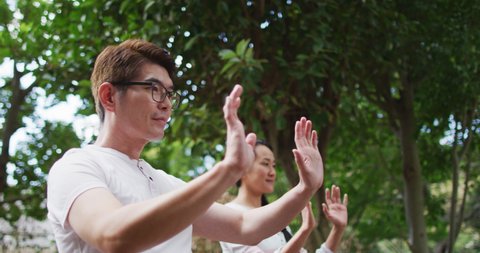 Happy asian couple exercising in garden with daughter, practicing tai chi together. happy family, at home in isolation during quarantine lockdown.