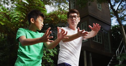 Happy asian fother exercising in garden with sonr, practicing tai chi together. happy family, at home in isolation during quarantine lockdown.