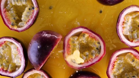 Passion fruit falling and splashing into water on yellow background in slow motion.  Juicy fresh summer passion fruits splashing into juice.