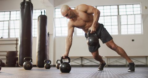 Fit caucasian man working out with kettle bells at the gym. sports, training and fitness concept