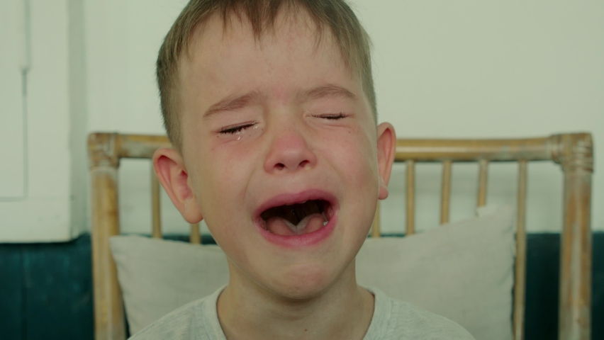 Portrait of a Cute boy with big tears running down his cheeks,child sits at the table at home and cries with his mouth wide open,tears are flowing with a screaming face.Child, not holding back his cry | Shutterstock HD Video #1074016484