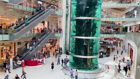 Moscow, Russia, May 2021: Inside a huge shopping mall Aviapark. Top view of several floors, escalators, a crowd of people. In the center is a huge aquarium with fish