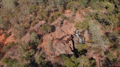 Super wide aerial view of Hidden Falls Regional Park waterfall flowing through the golden Auburn, California mountains