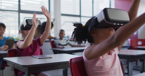 Diverse schoolchildren sitting in classroom wearing and using virtual reality glasses. children at primary school.