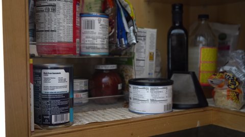 Stocking a pantry shelf with canned goods - 4K
