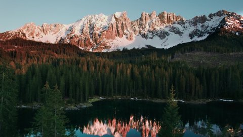 Karer See , South Tyrol , Italy - 05 26 2021: Mountain range is reflecting in lake during sunset. Karer Lake South Tyrol - Dolomites