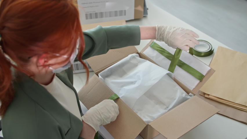 fashion boutique, young woman in protective mask and medical gloves packing goods for online clothing store buyers working in quarantine Royalty-Free Stock Footage #1074051503