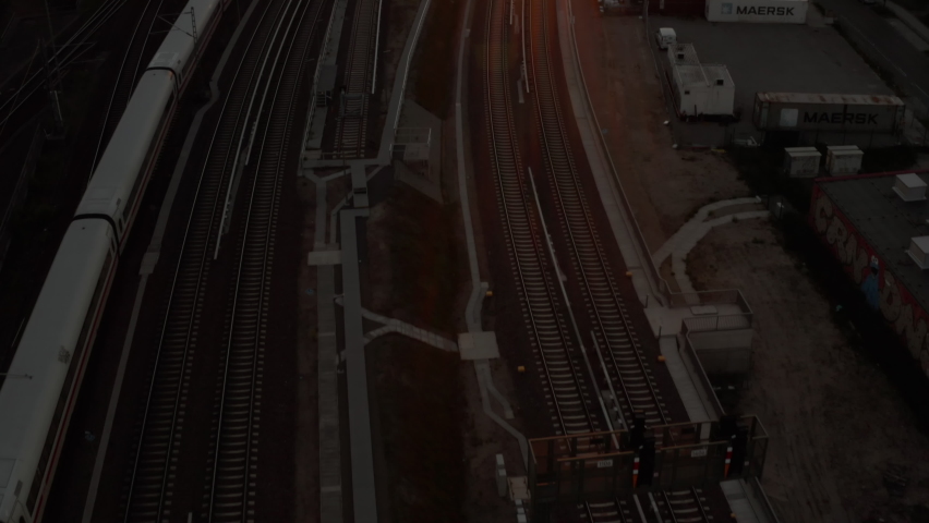 Beautiful Establishing Shot of white passenger Train on driving into Sunset over Berlin, Germany Golden Hour Cityscape and Ostbahnhof Central Train Station, Aerial Wide Angle  Royalty-Free Stock Footage #1074052451